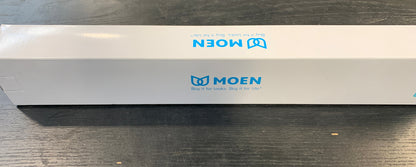 A long white MOEN product box with blue logo printing, placed horizontally on a dark wooden table.